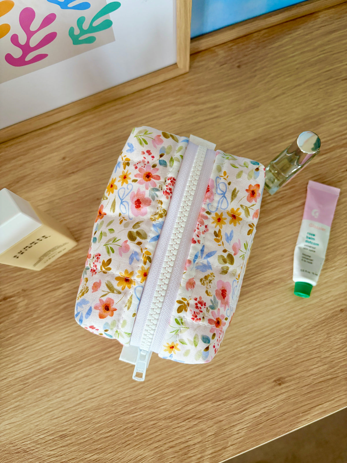 Bright floral mini makeup bag opened with white zipper; pink gingham-lined interior