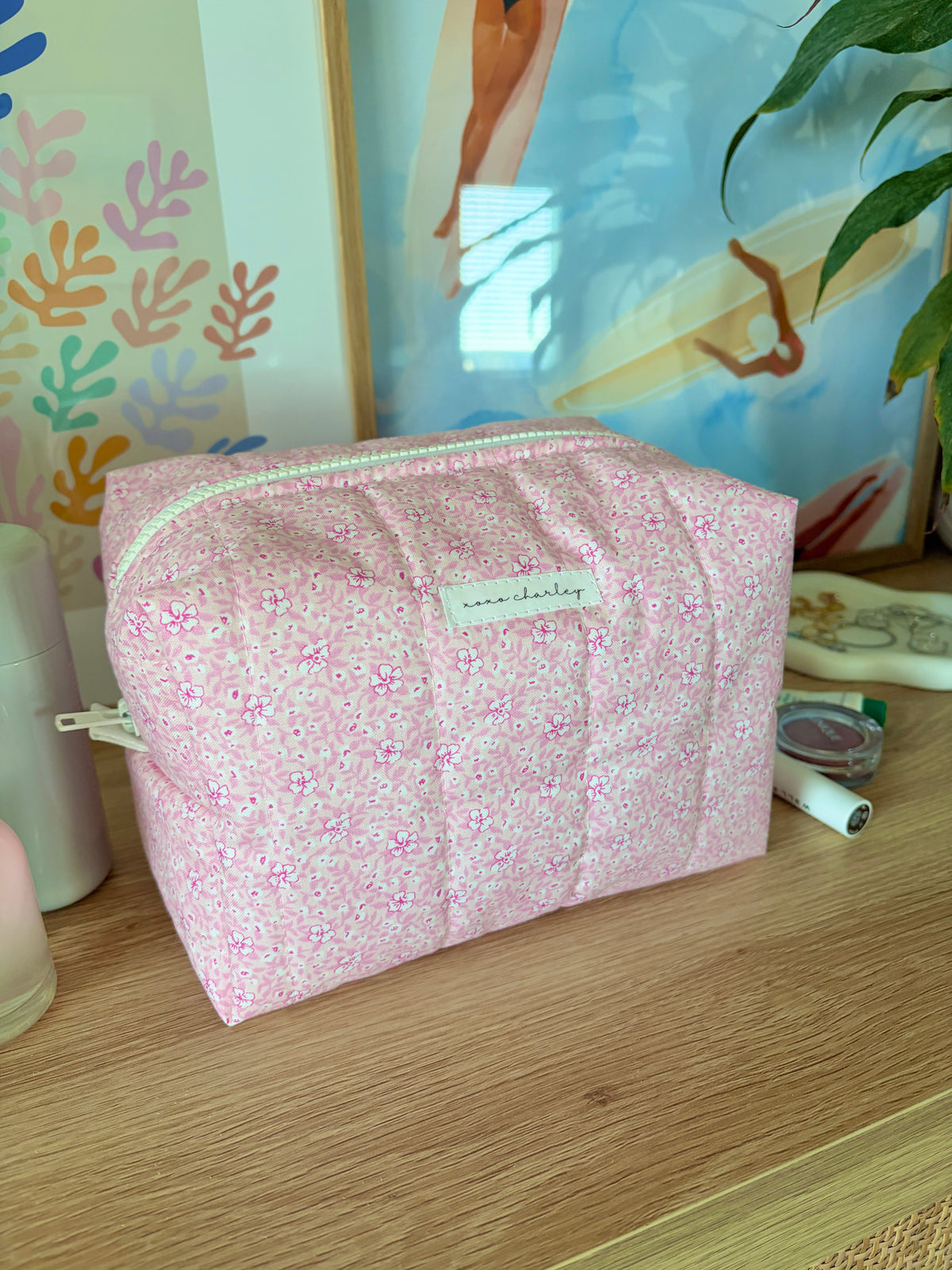 Pink floral makeup bag with mint zipper stripe and woven-look handle loop detail.