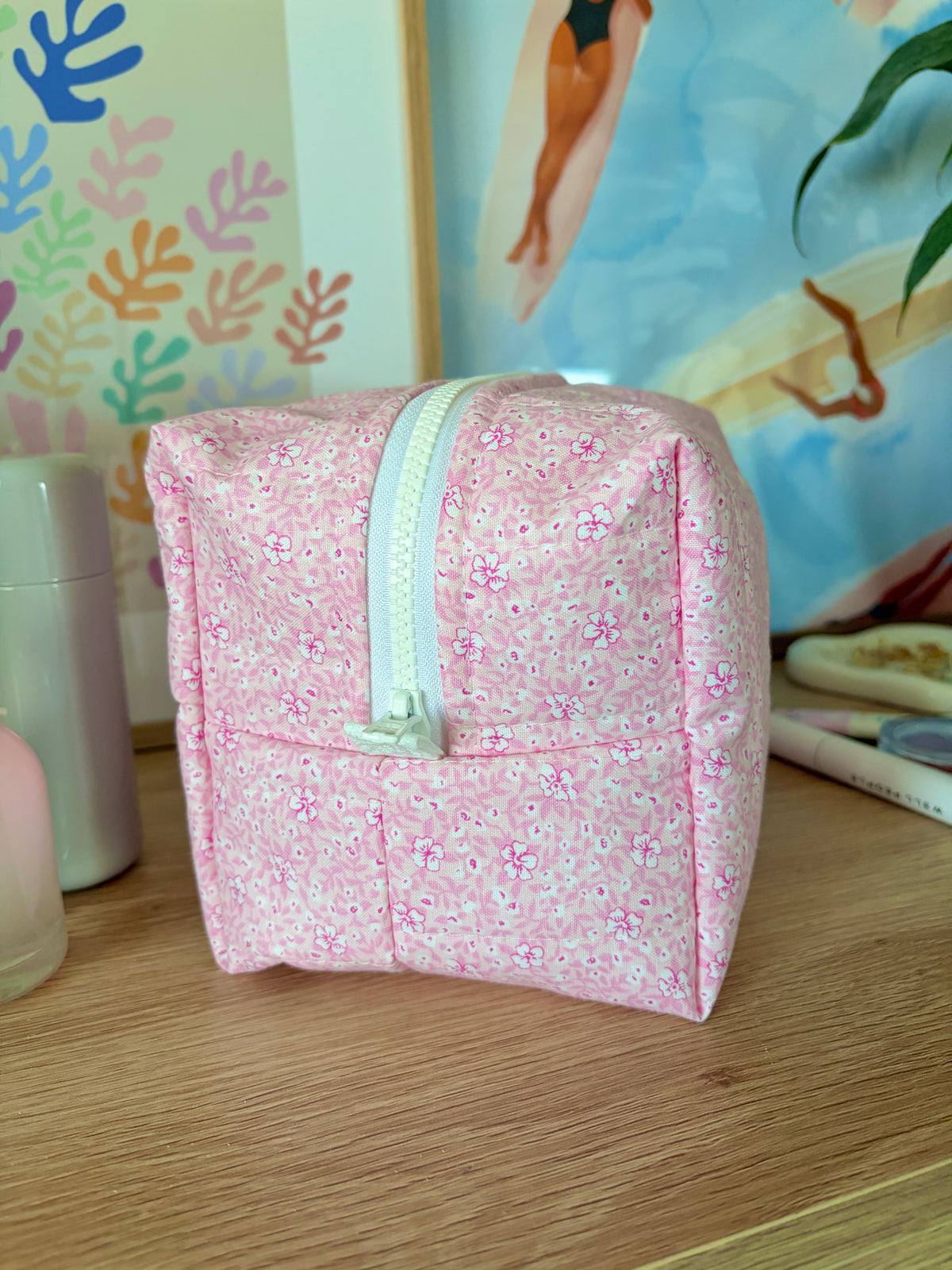 Pink glitter makeup bag standing upright with front zipper and mint color trim.