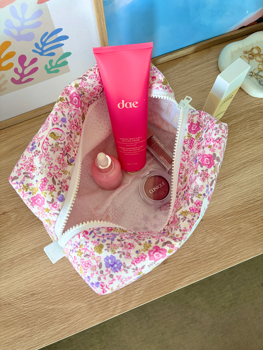 Large pink floral makeup bag open with beige interior and white zipper trim.