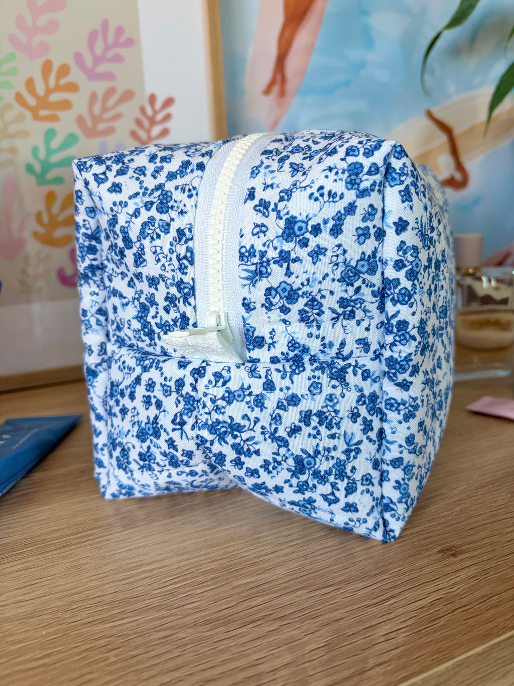 Large blue floral makeup bag, side view with white trim and zipper