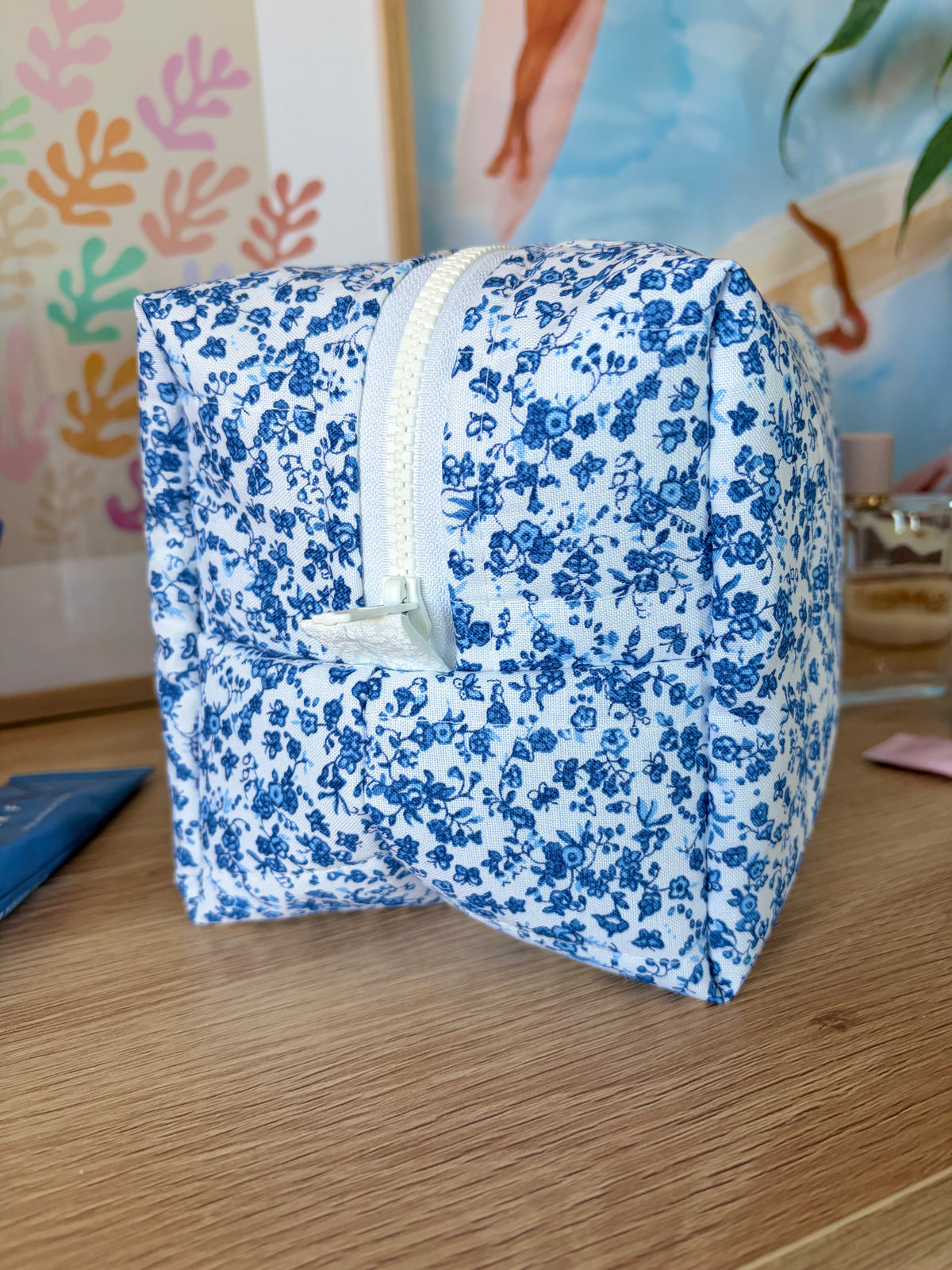 Large blue floral makeup bag, side view with white trim and zipper