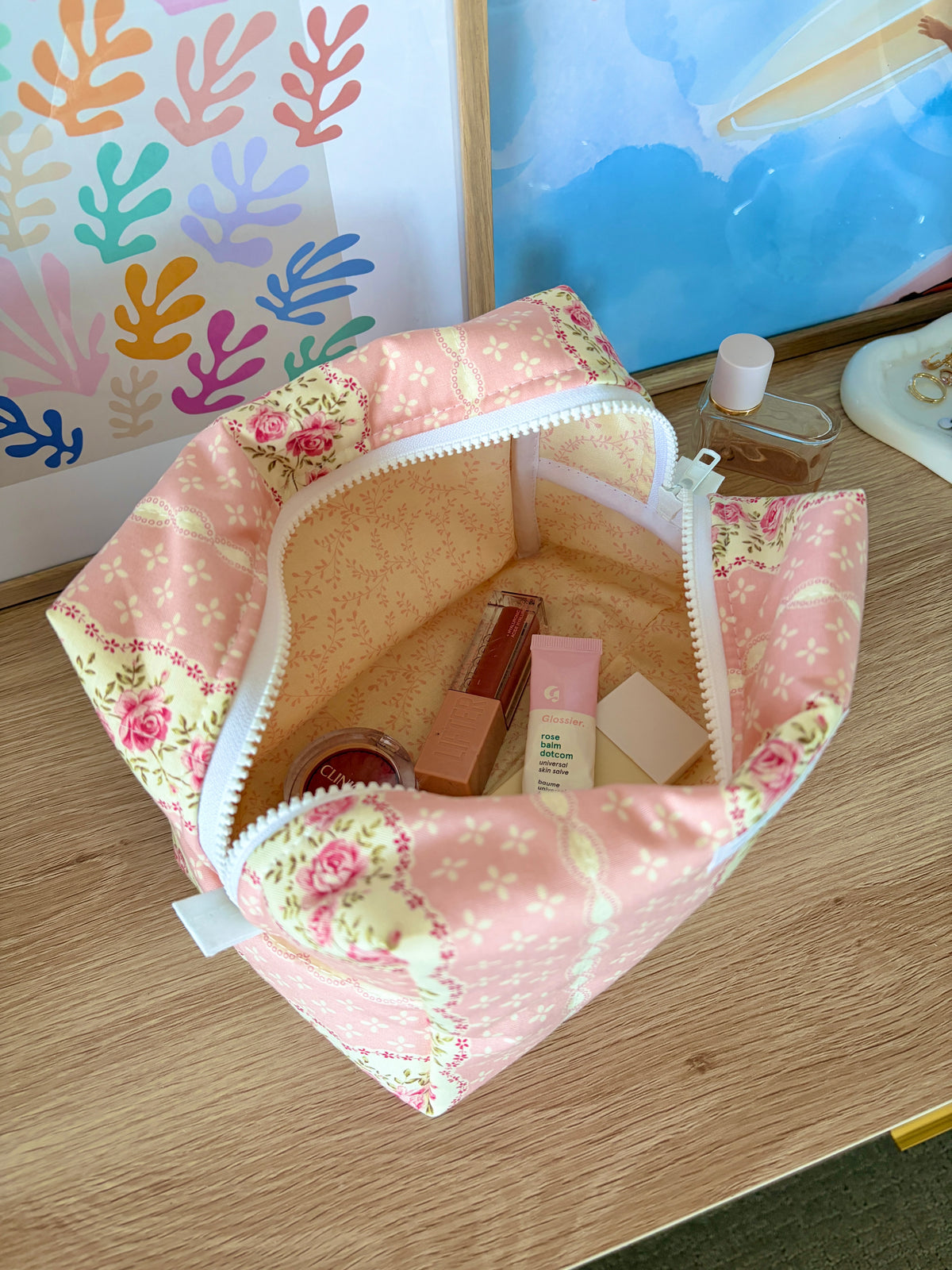 Open pink floral makeup bag with interior organizer pockets and multiple products