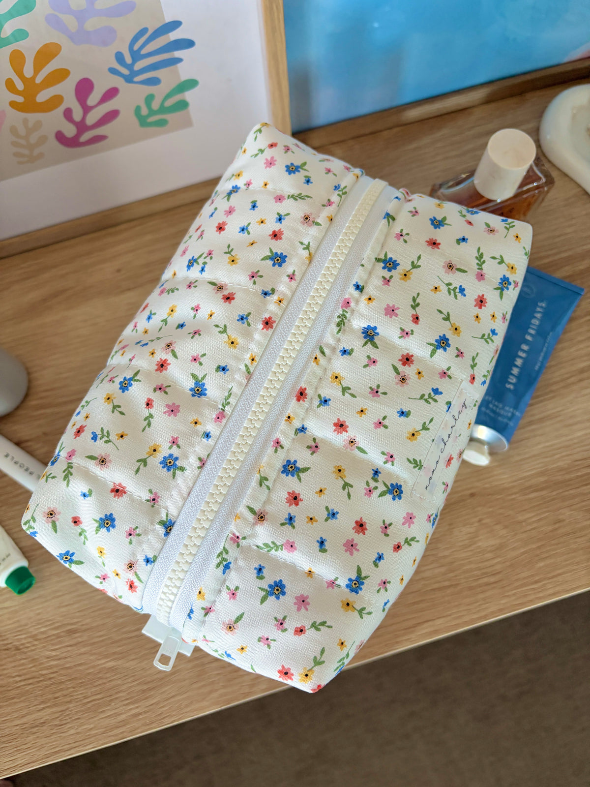 White floral makeup bag with long zipper, angled side view