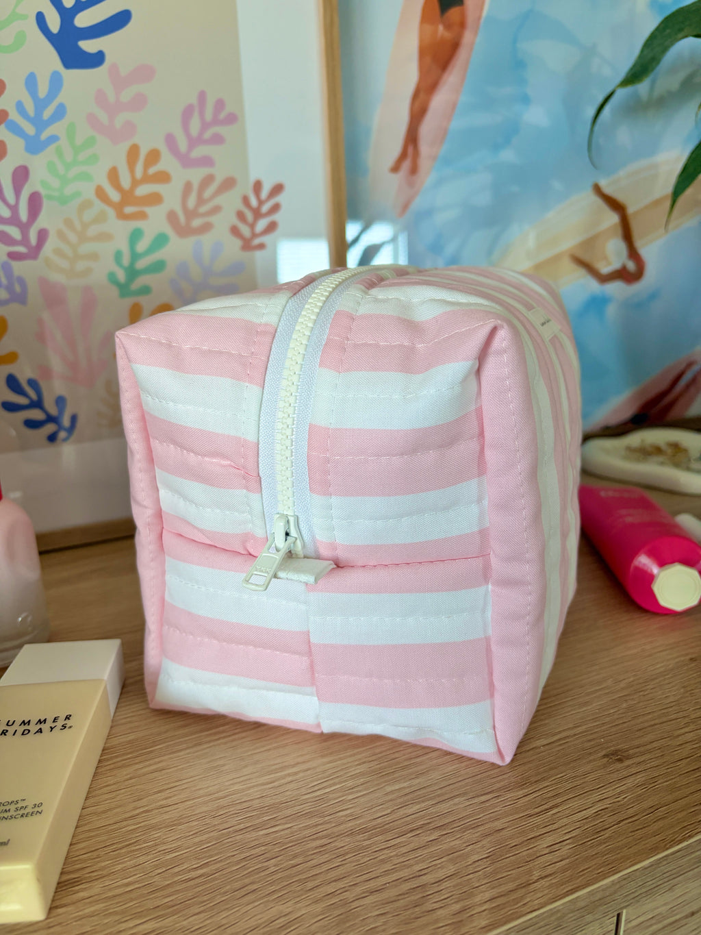 Pink and white striped makeup bag with front pocket panel and zip closure