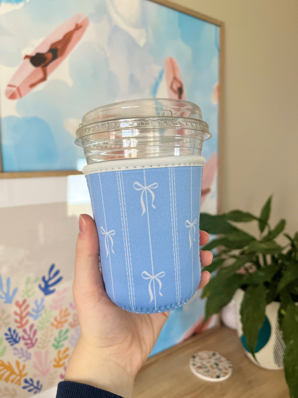 Blue cup sleeve with bow pattern, designed to fit a small drink cup.