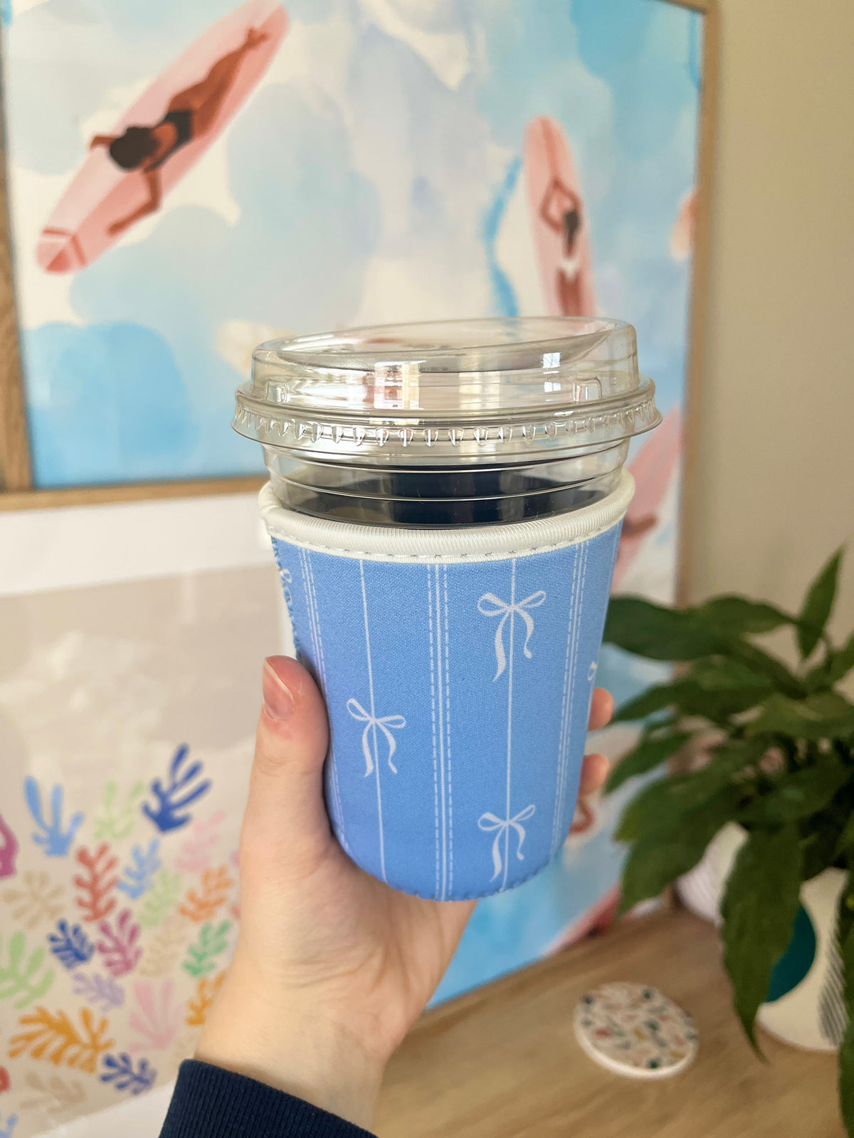 Blue cup sleeve with bow motifs, shown wrapped around a small cup with lid.