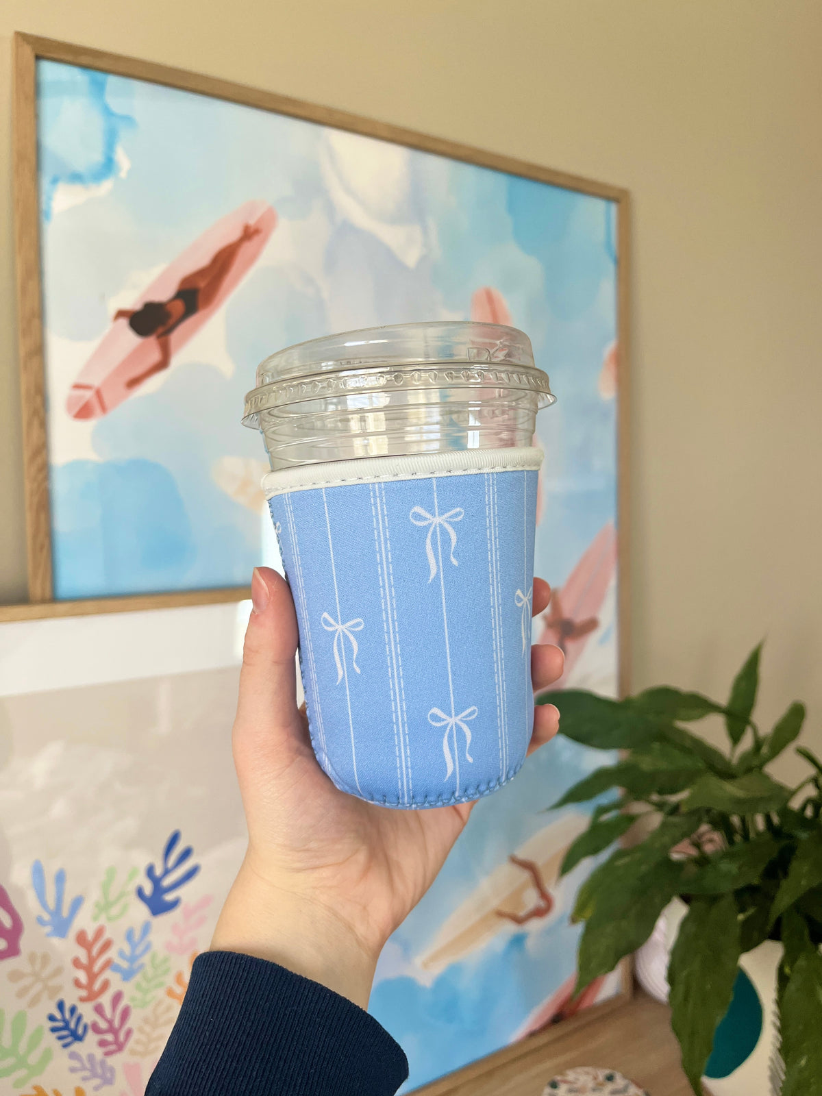 Blue cup sleeve with bow icons, angled view with rim and stitched seams visible.