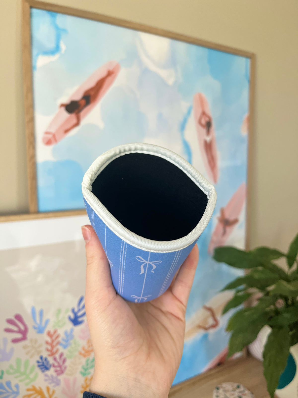 Small blue cup sleeve with bow design, open top revealing dark interior.
