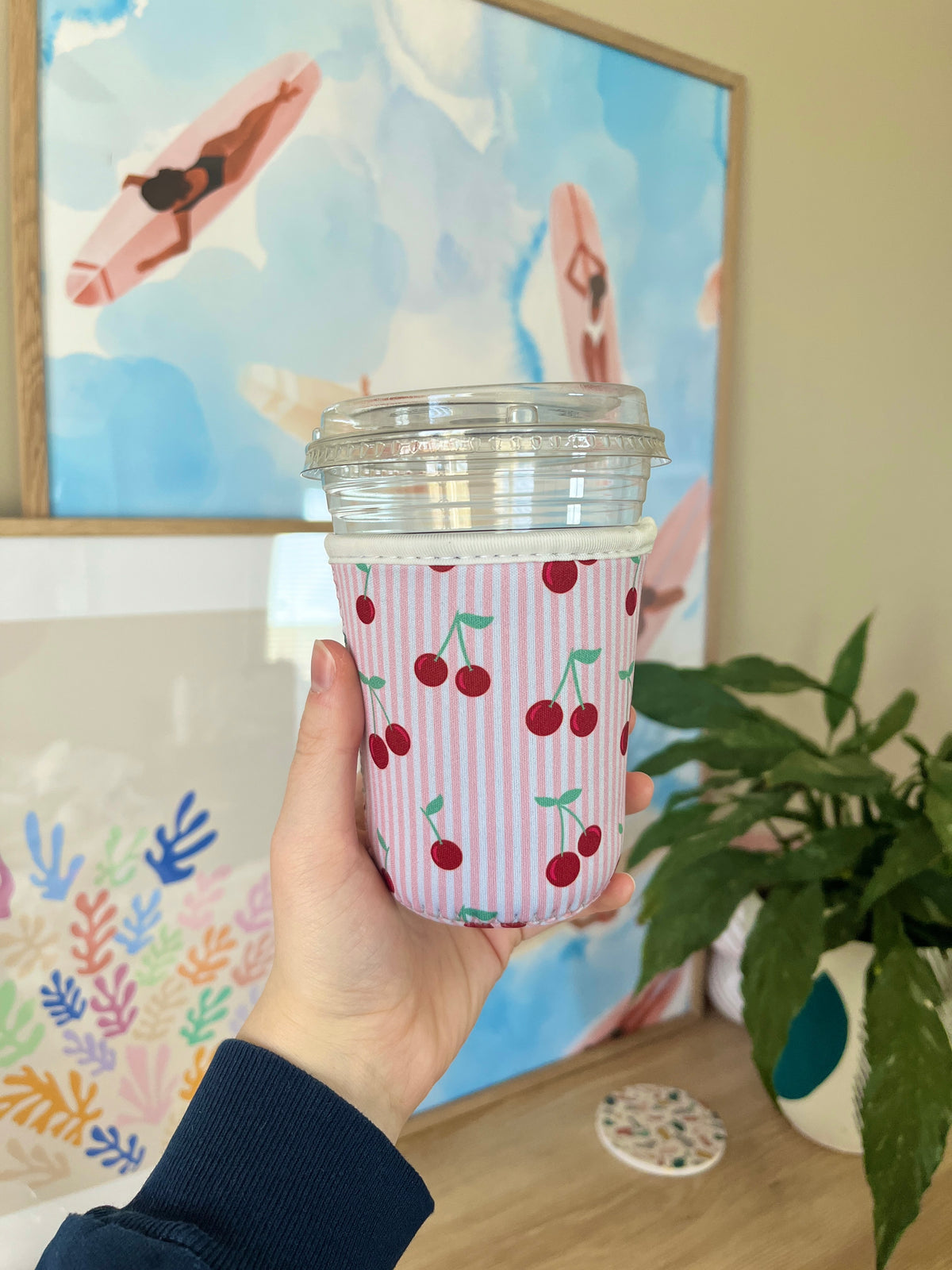 Small pink cup sleeve with striped pattern and red cherry print around drink cup