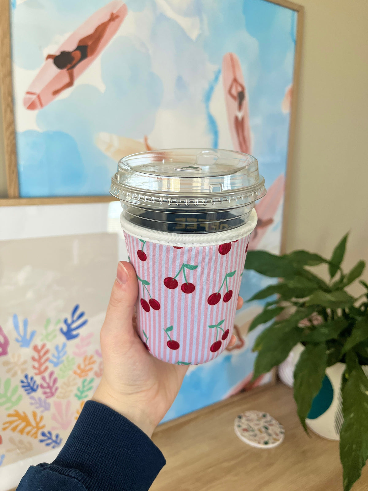 Pink striped cup sleeve with red cherries, shows lid opening on small cup