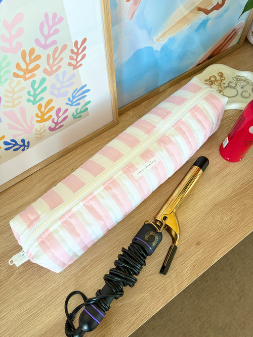 Pink and white striped hair tools bag with tools arranged inside and zip top