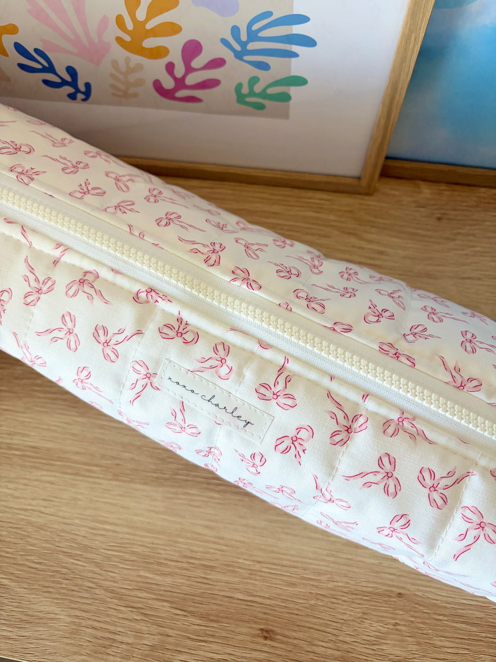 Hair tools bag with pink bow print and pale zipper trim, close-up view