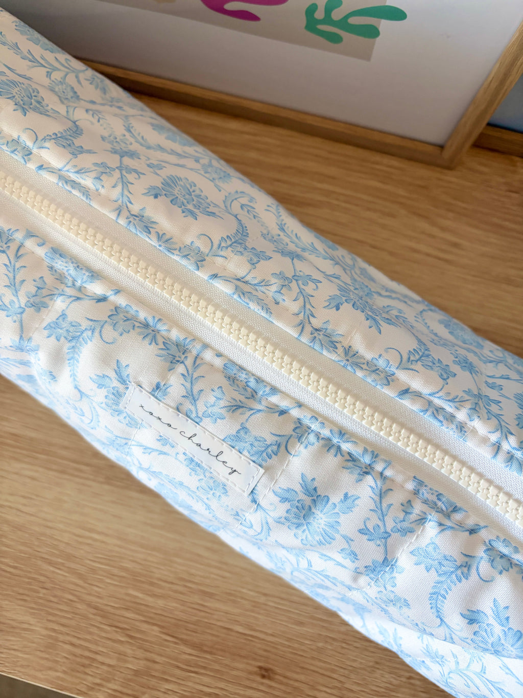 Light blue floral hair tools bag detail with cream zipper and decorative fabric pattern