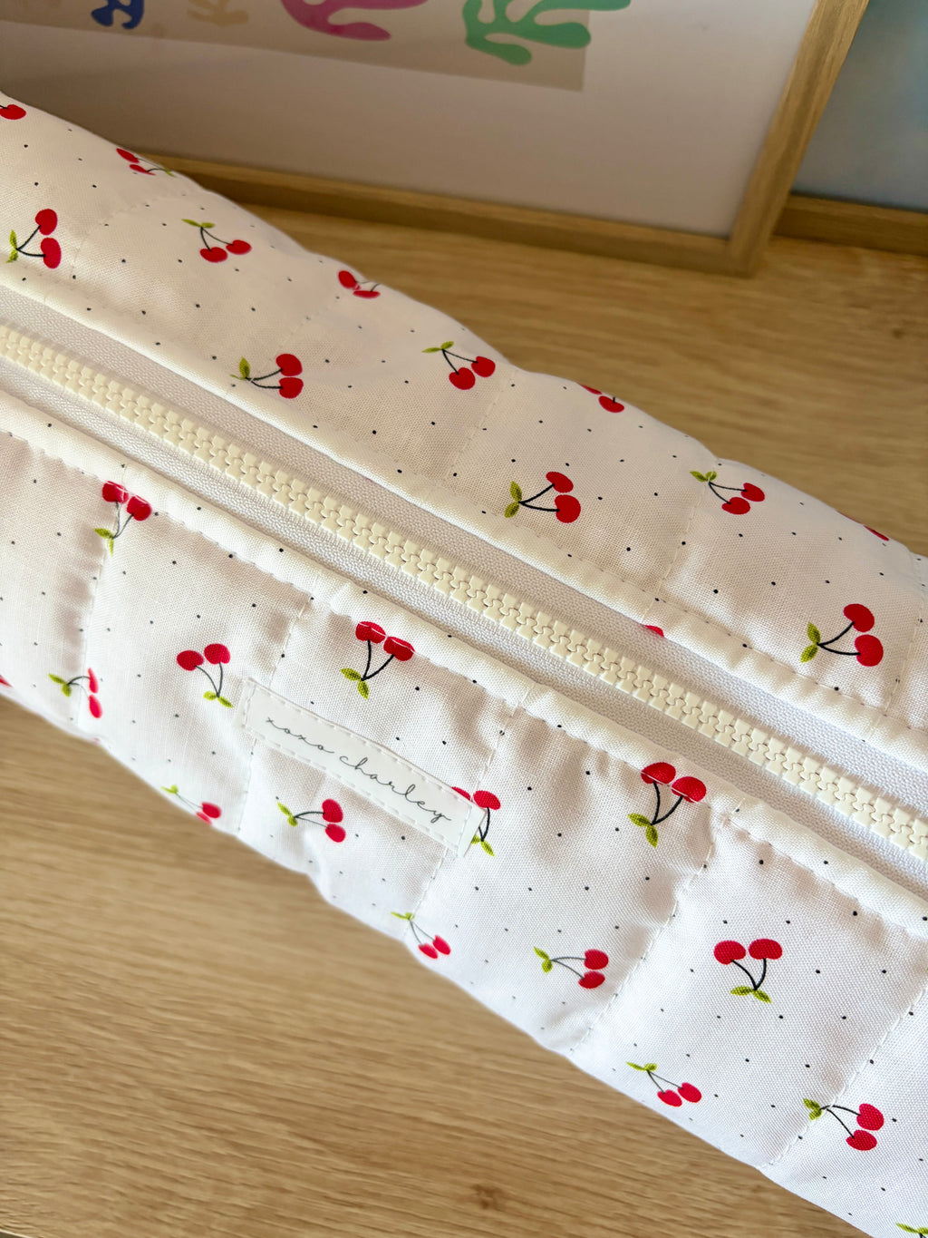 Cream cherry print hair tools bag close-up of gold zipper and stitched front pockets