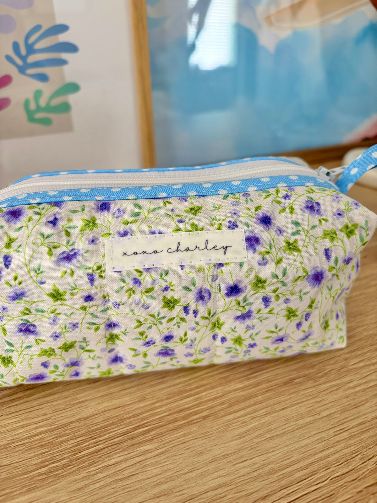 Floral fabric pouch with blue zipper stripe and stitched front panel