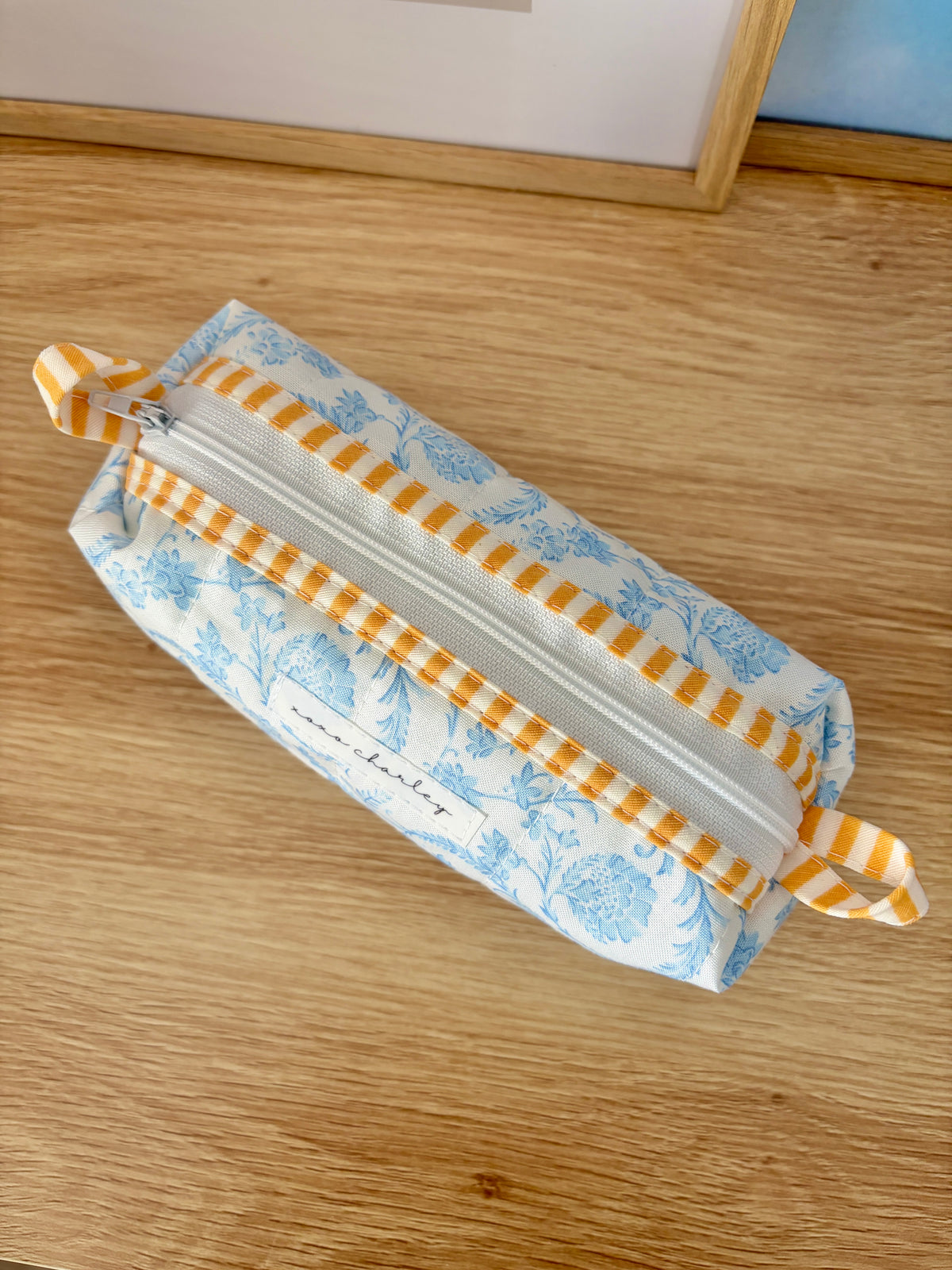 Blue floral zippered pouch with gray center stripe and orange gingham edging