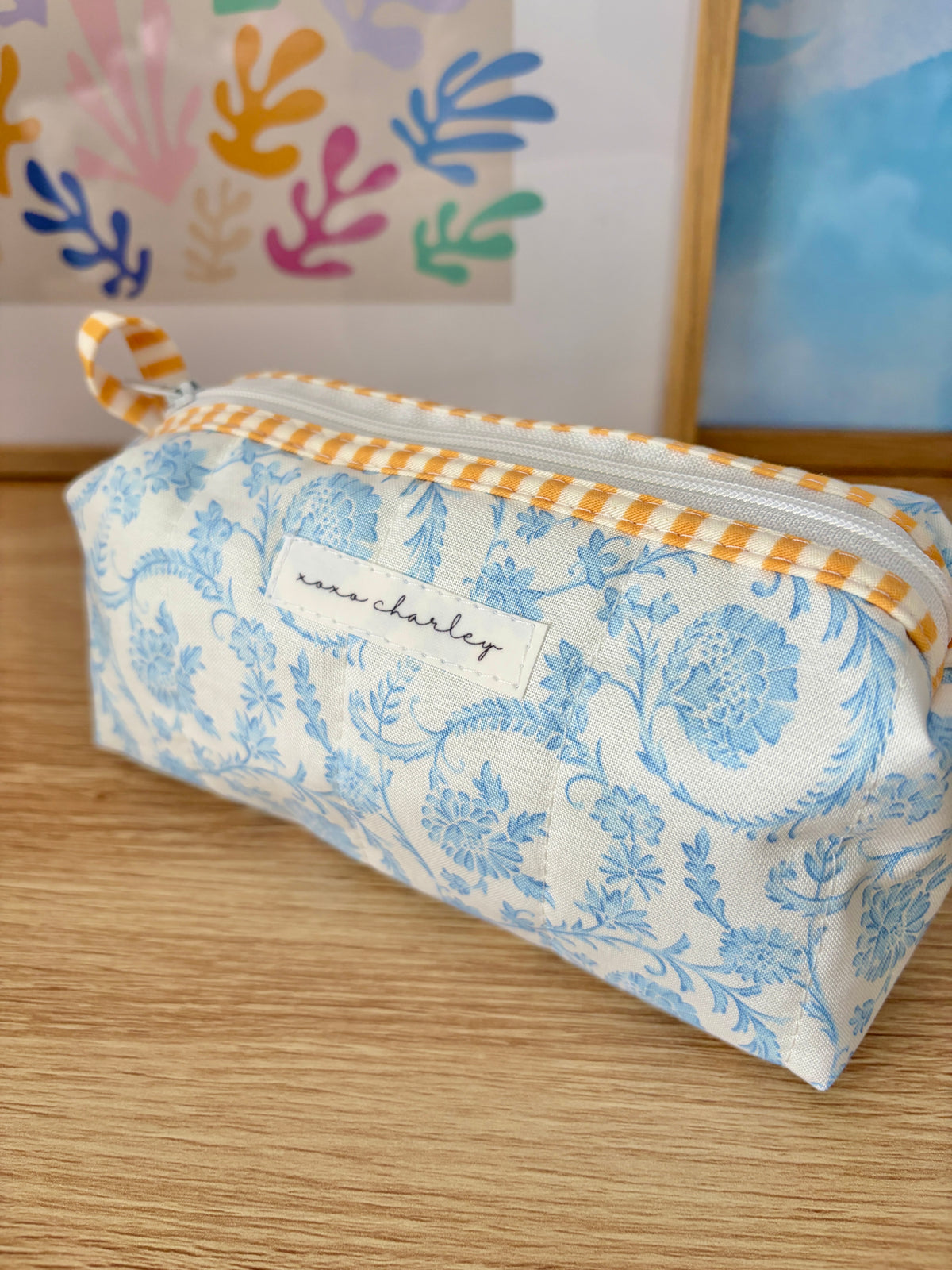 Blue floral pencil pouch with gray stripe band and orange gingham ribbon ties