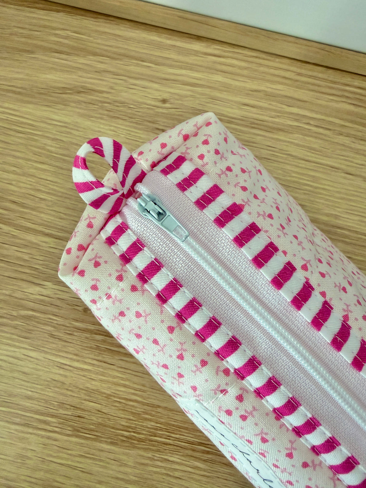 Pink heart print zip pouch with magenta striped panel, bow tie and metal zipper pull