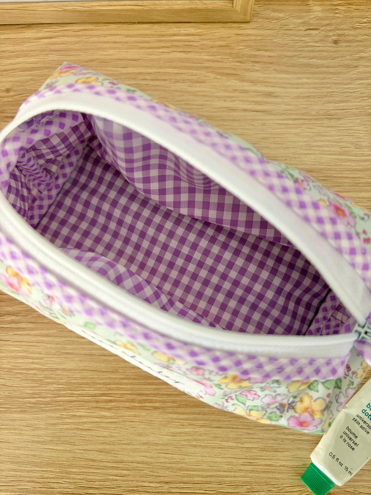 Purple gingham-lined zip pouch bag with floral outer and visible zipper opening