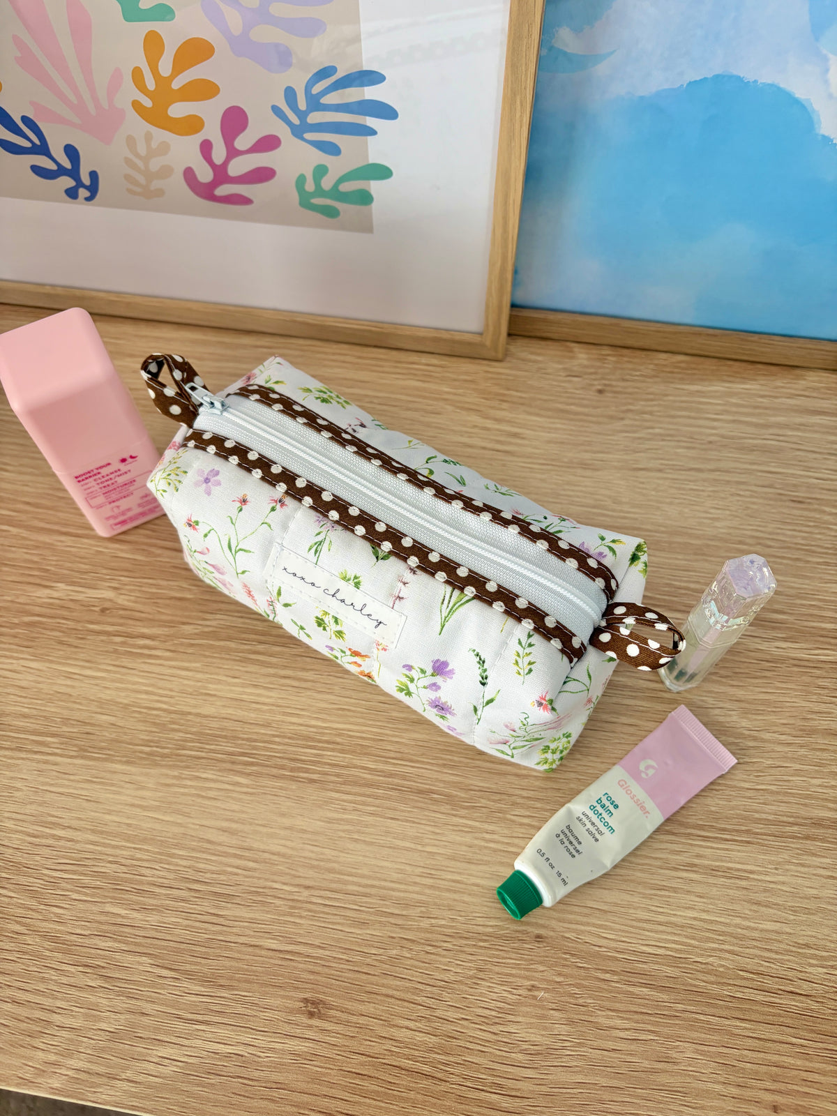 Floral canvas wristlet with brown trim, white zipper, and green gingham lining