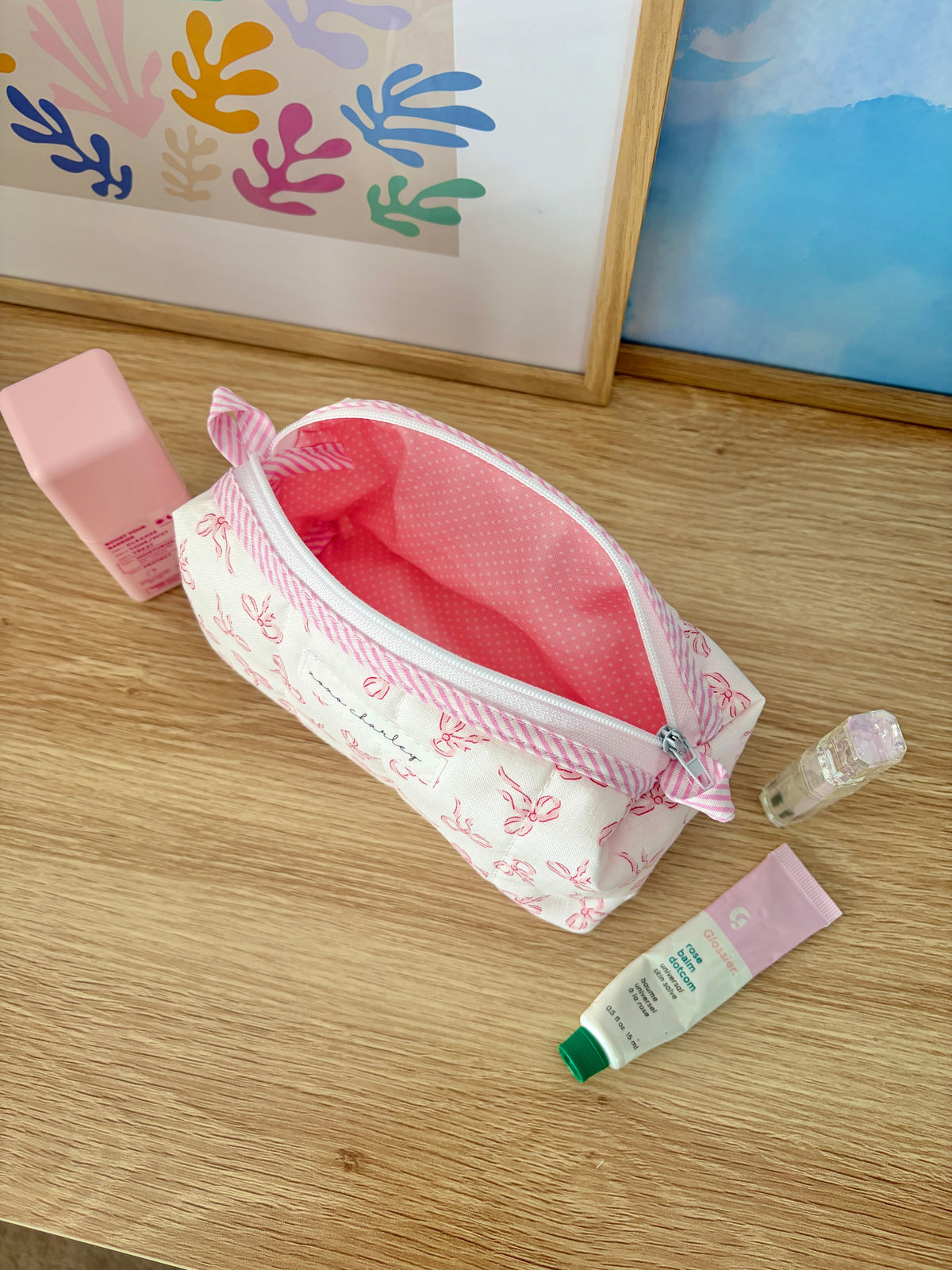 Pink and white bow mini zipper bag with red interior, striped trim, and tied bow