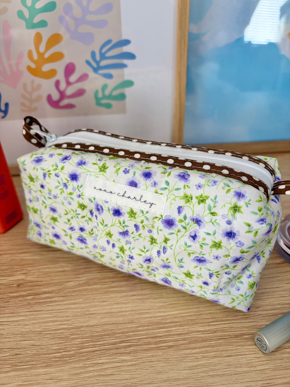 Floral zip pouch with brown trim and long zipper, front angle