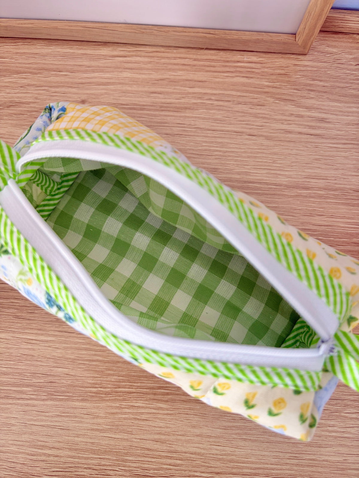 Green gingham zip pouch with white zipper and striped green trim