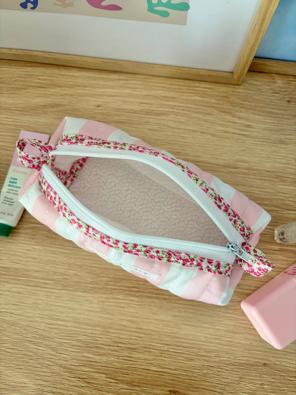 Pink and white striped zip pouch bag with floral trim and curved zipper opening