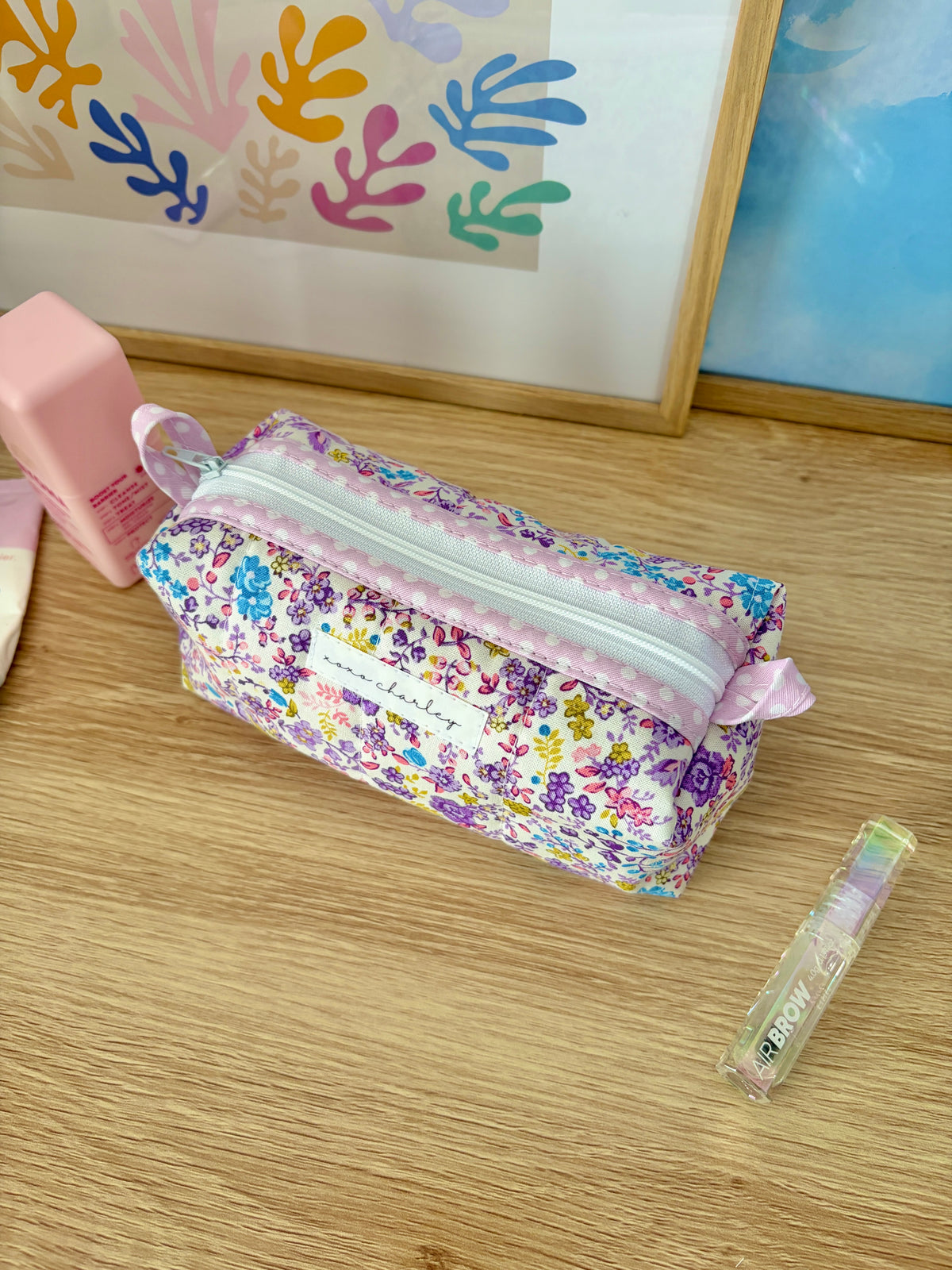 Purple floral zipper bag with light pink trim and bow detail at ends