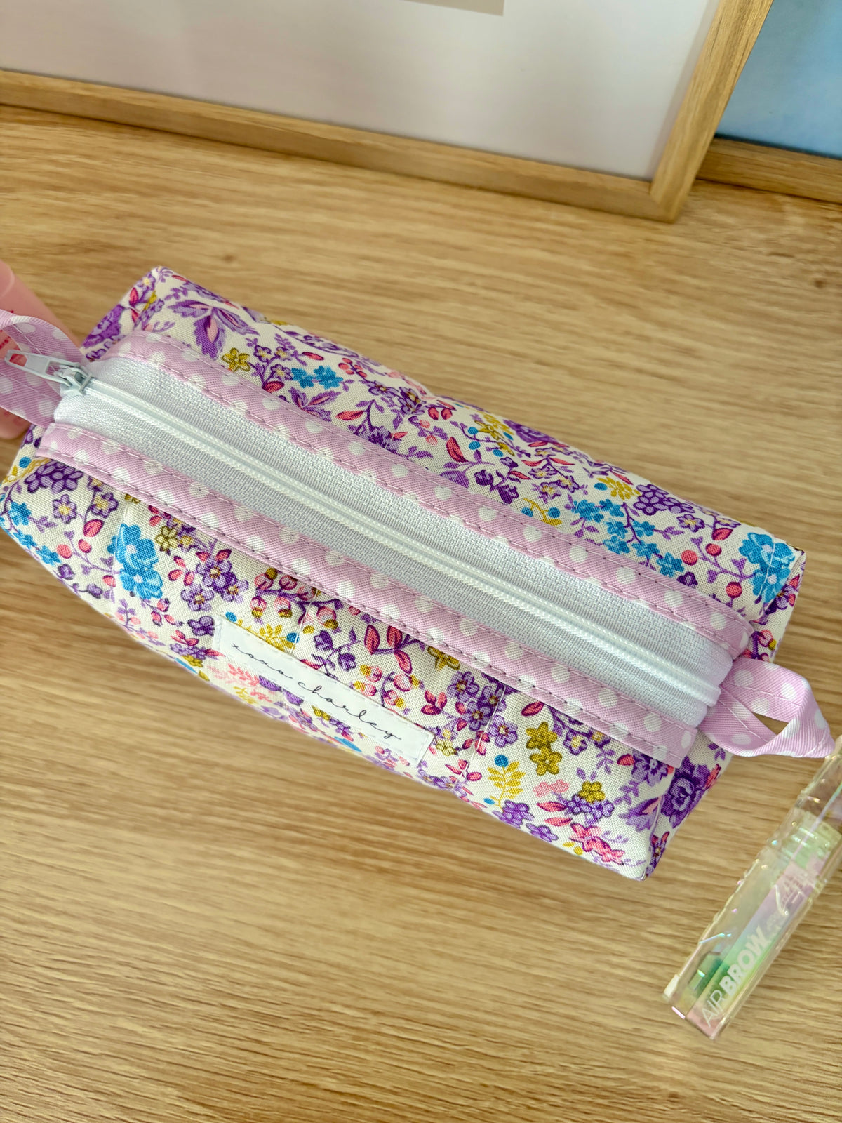 Purple floral zipper pouch with light pink trim and bow tie sides, open top view
