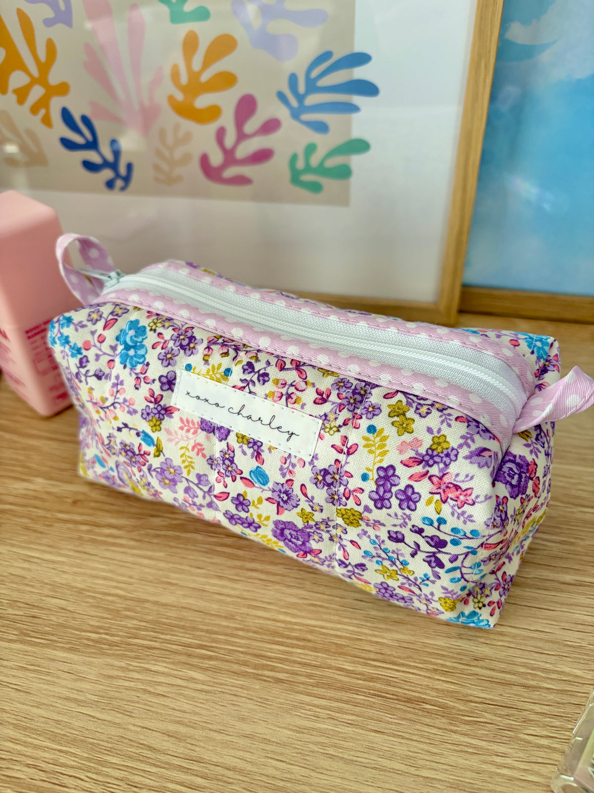 Purple floral zipper pouch with light pink trim and small front label panel