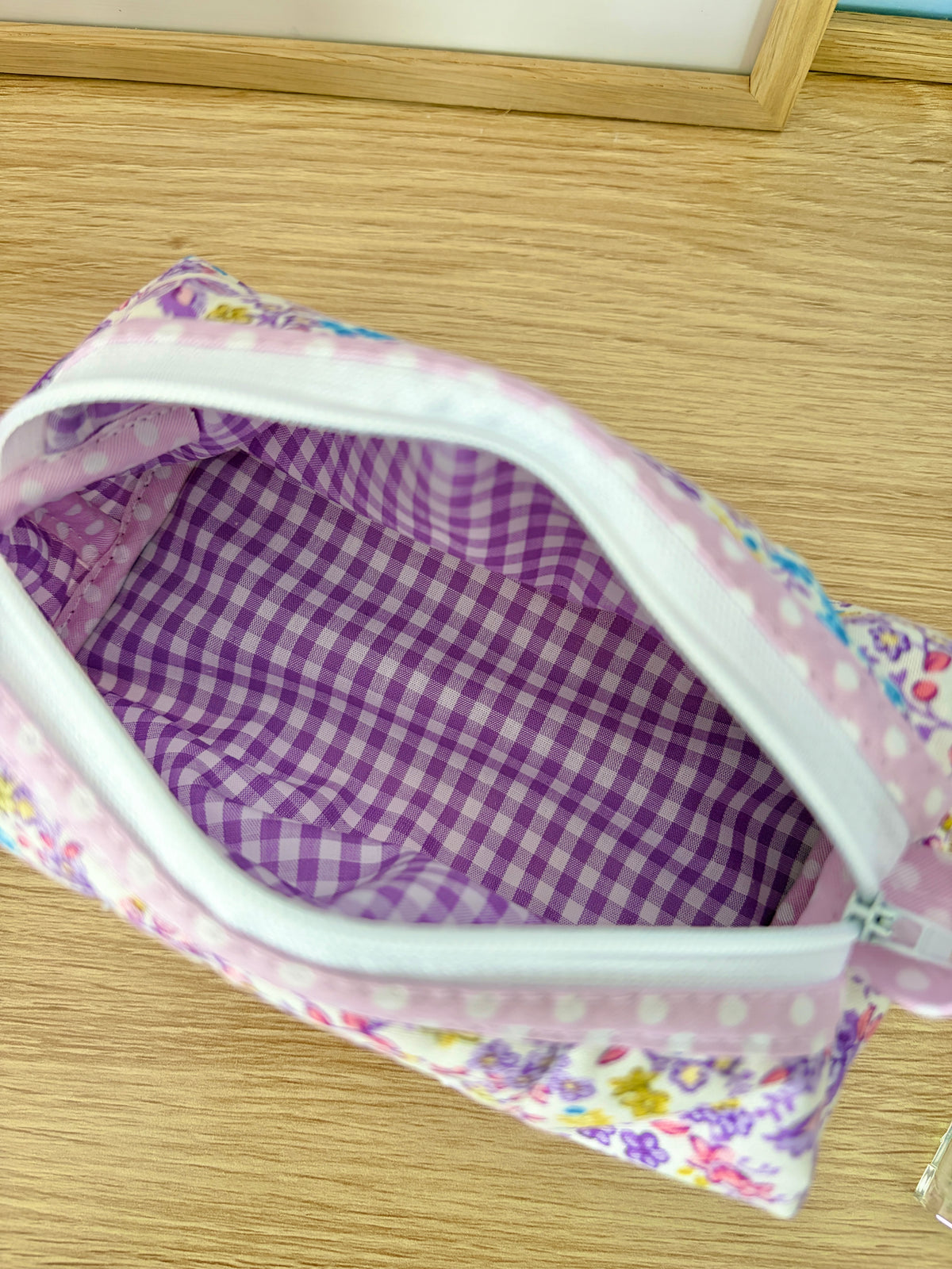 Purple gingham lining inside purple floral zipper bag with light pink trim border