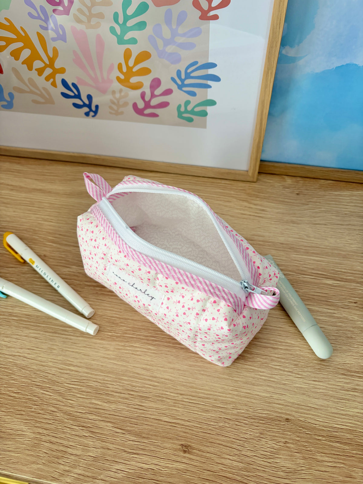 Pink heart print zip pouch with open top and light interior lining.