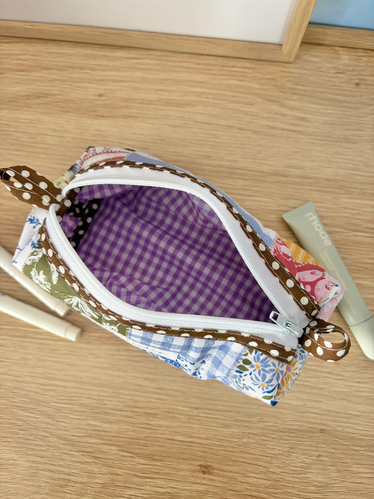 Open colorblock bag showing purple gingham lining, white zipper and brown trim