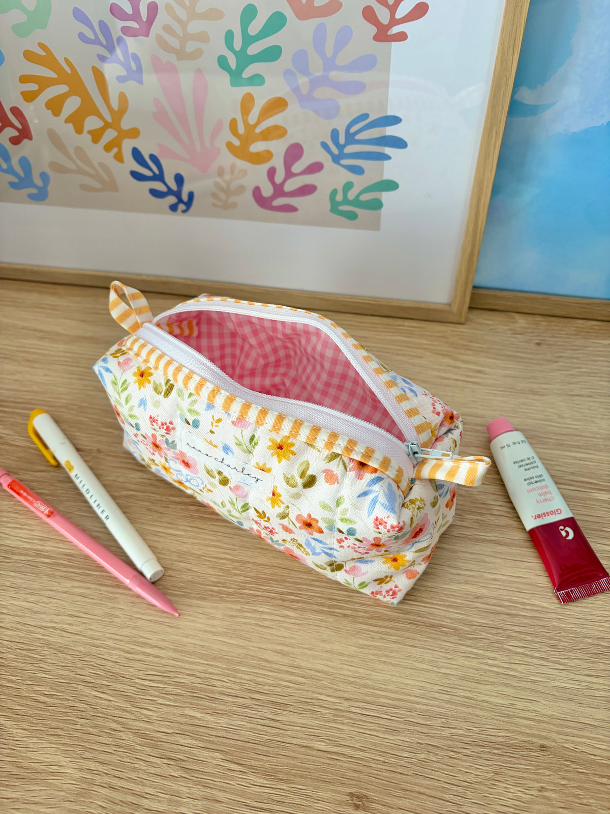 Floral zip pouch with yellow stripe trim and visible pink gingham interior lining