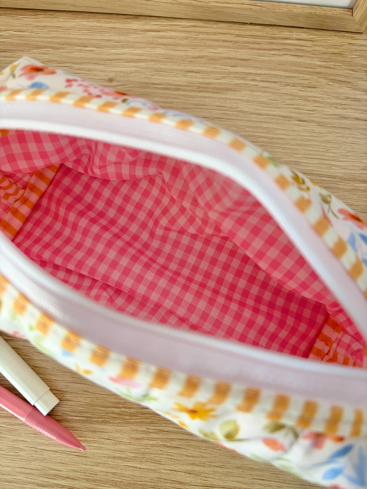 Floral zip pouch close-up showing pink gingham lining and white zipper tape