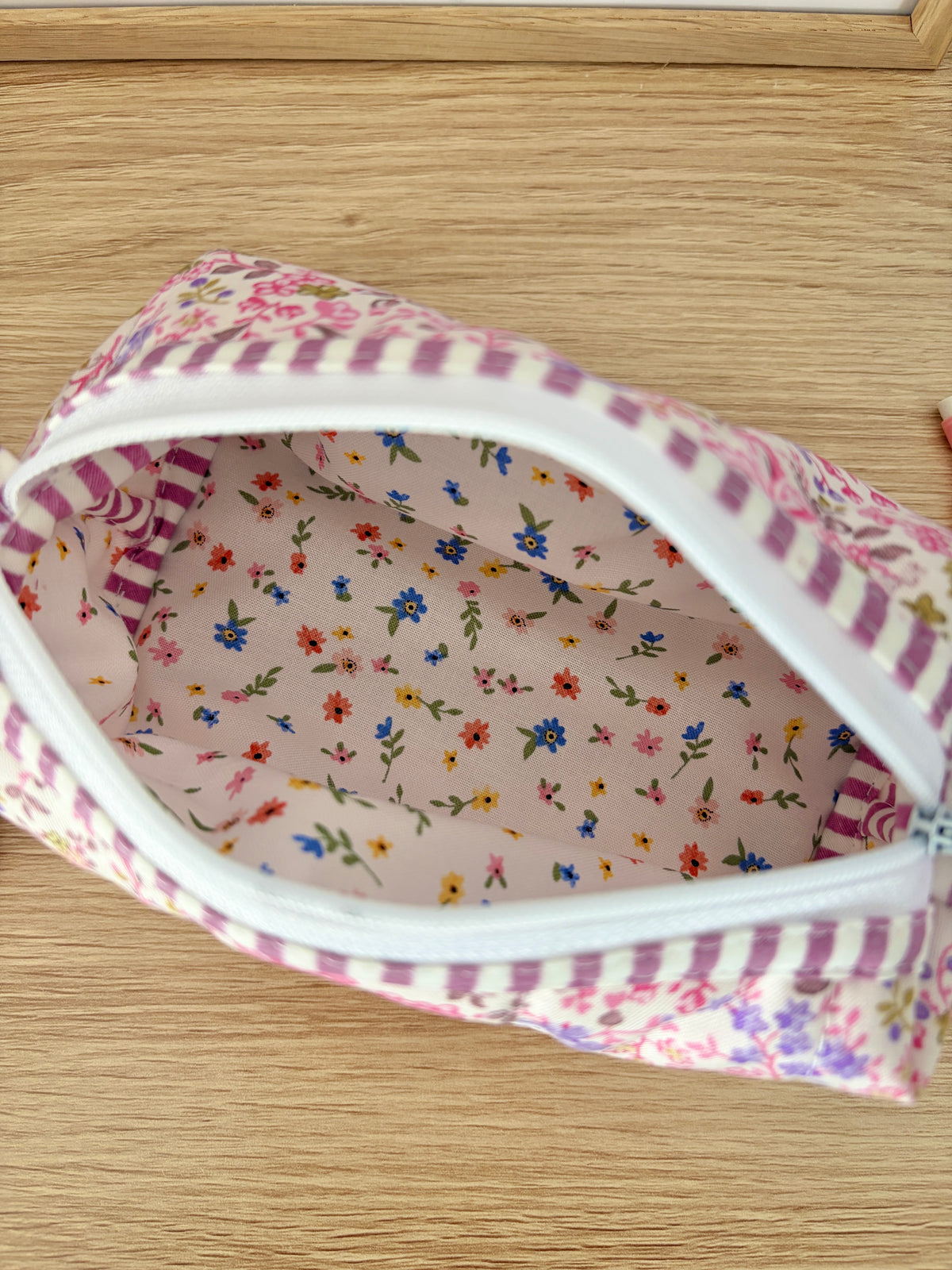Close-up of floral lined zip pouch interior with pink and white striped trim