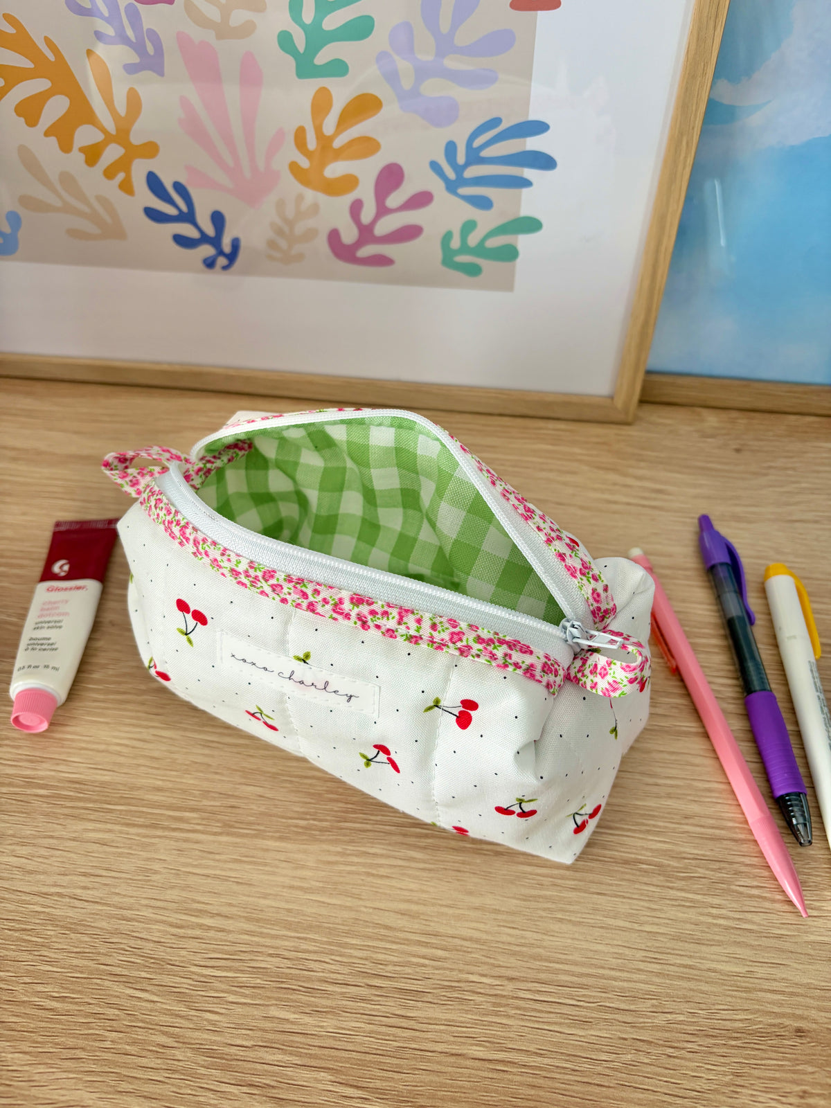 Cherry print colorblock zip pouch bag, open to show green gingham interior and pink trim