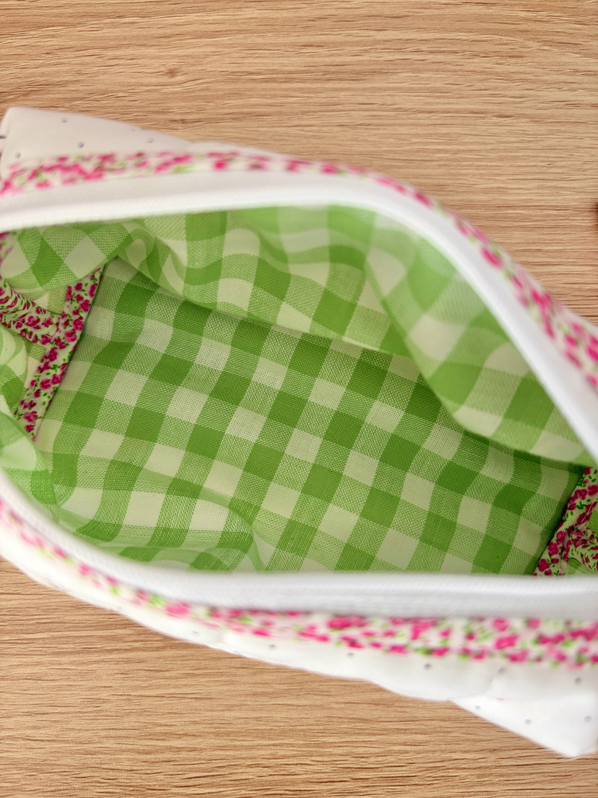 Close-up of open cherry print zip pouch showing green gingham lining and pink floral zipper trim