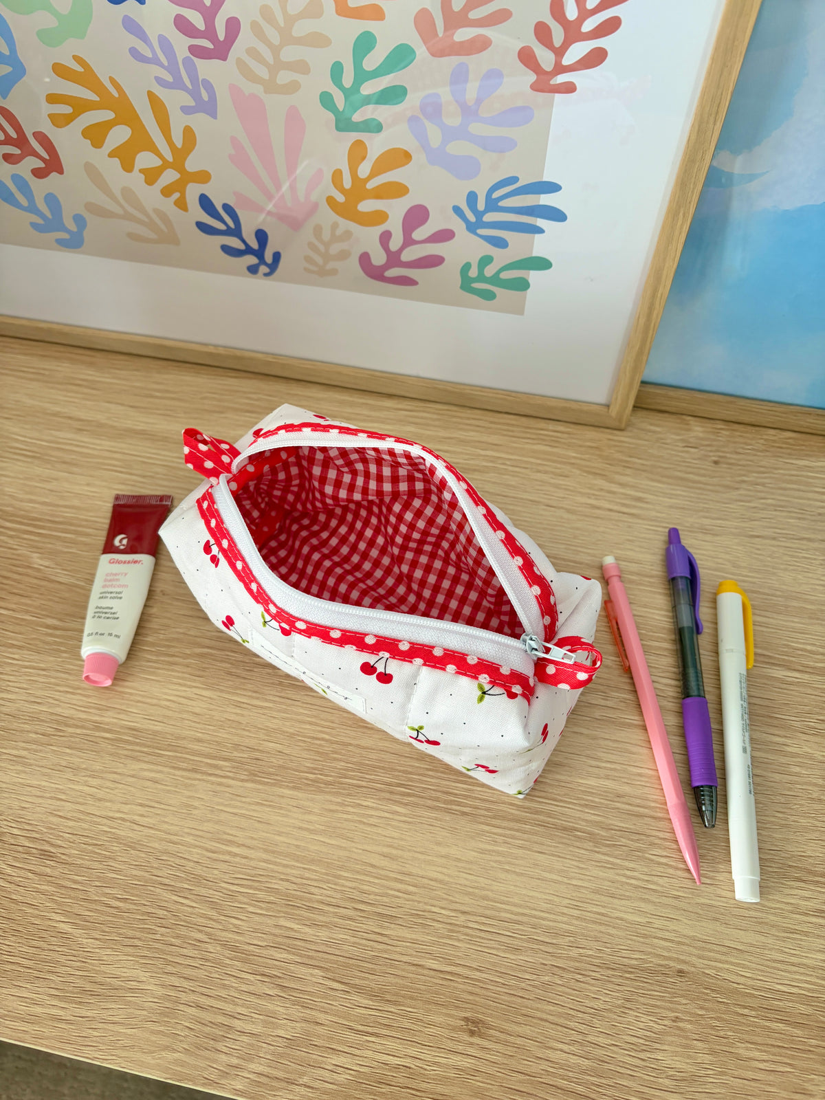 Small pouch with red gingham lining, red zipper, and cherry print exterior