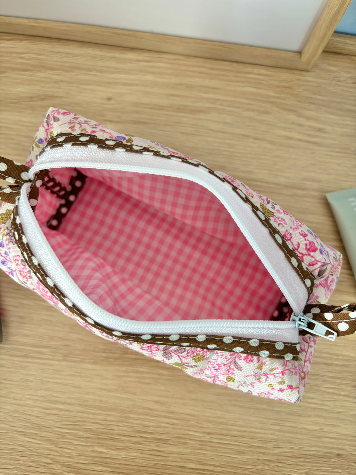 Open pink floral zip pouch bag showing pink gingham interior and white zipper