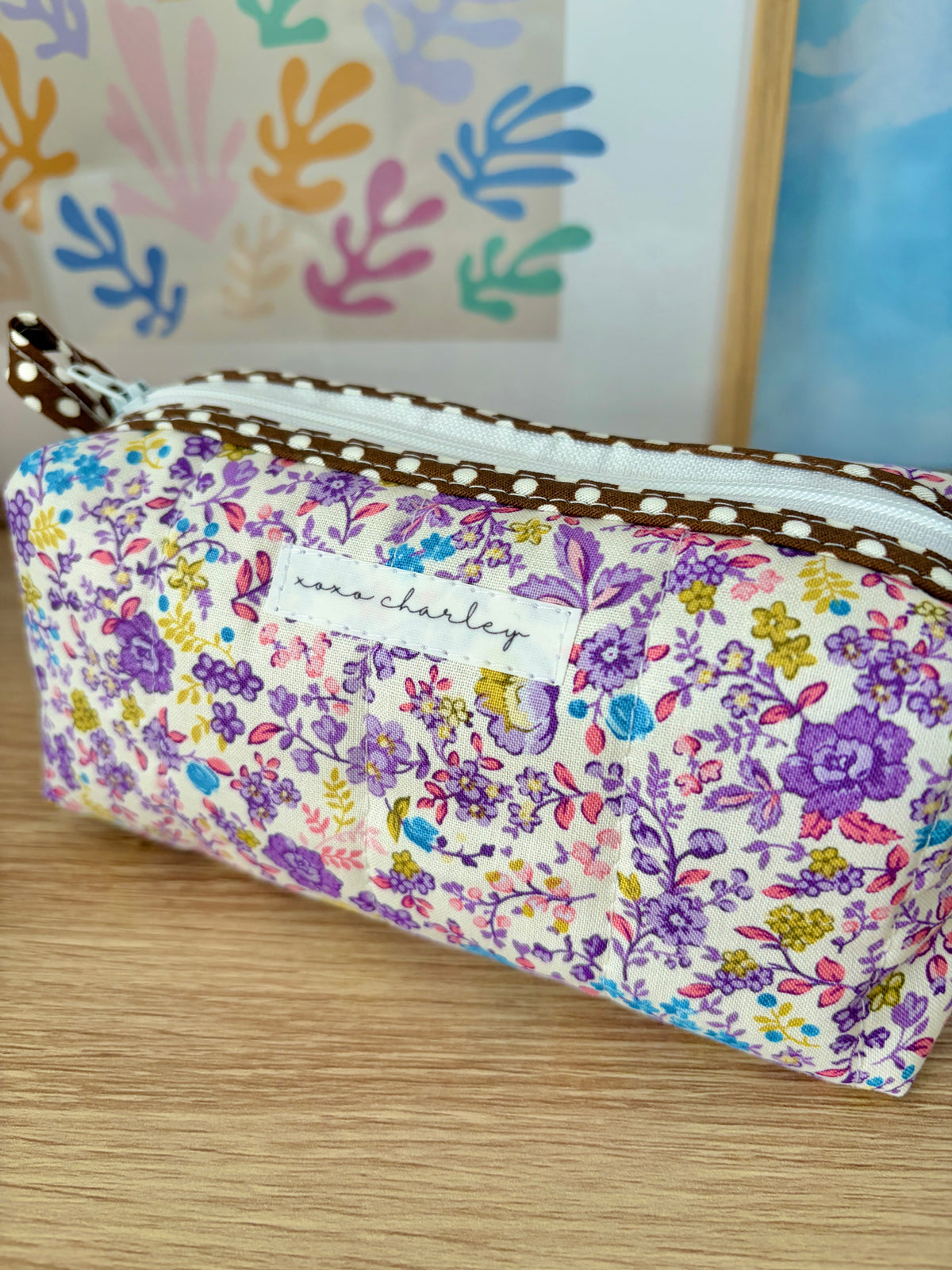 Purple floral zip pouch with front zipper and stitched brown trim