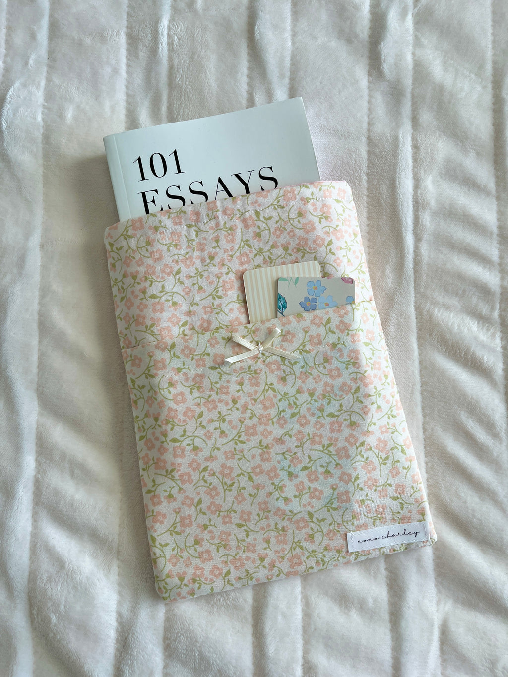 Floral medium book sleeve with stitched label pocket and hanging ties, angled view