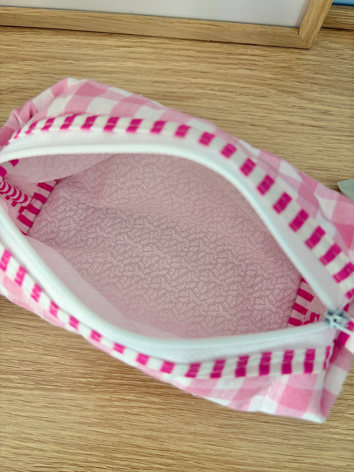 Pink gingham zip pouch open, light pink textured lining visible inside