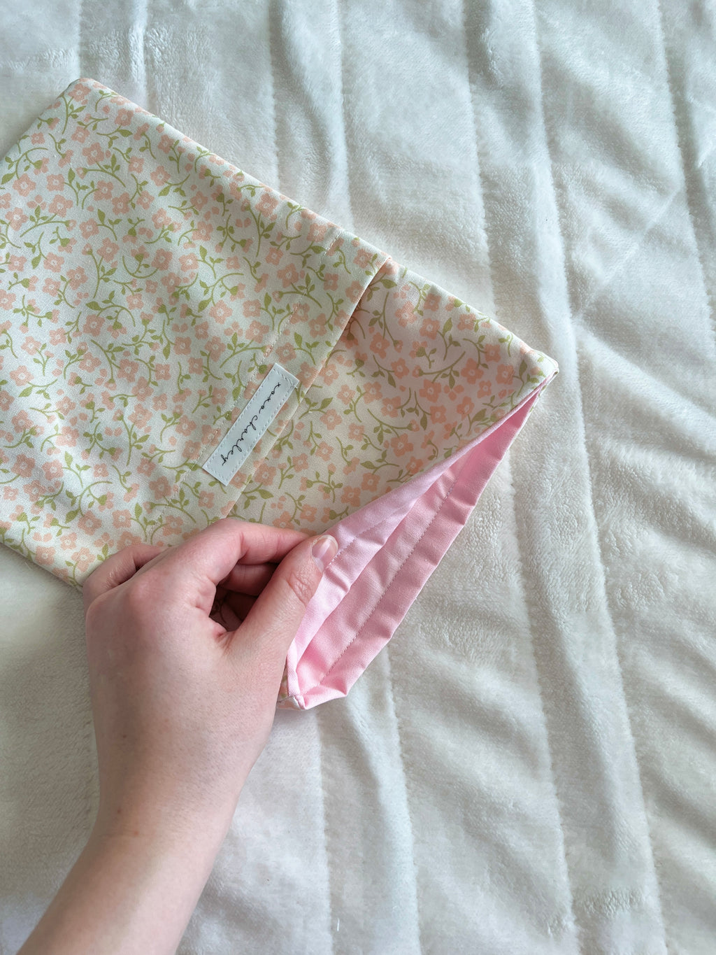 Floral medium book sleeve with pink side cuff and drawstring ties, handheld close-up