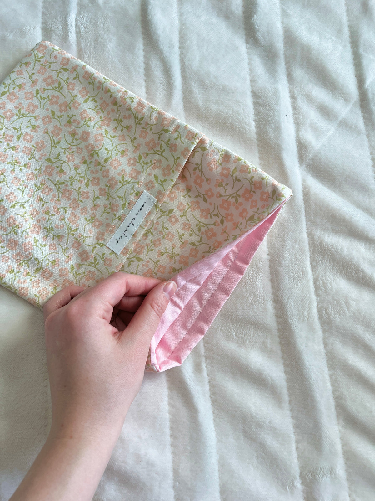 Floral medium book sleeve with pink side cuff and drawstring ties, handheld close-up