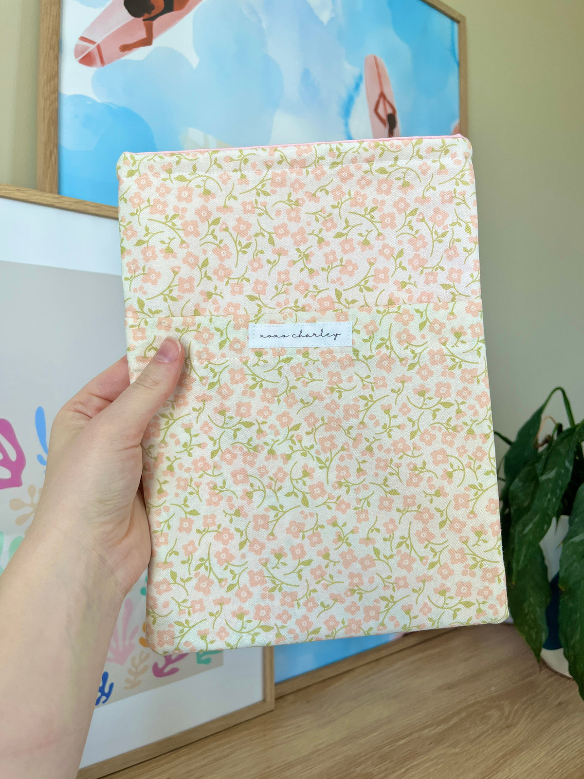 Floral medium book sleeve with front pocket label and pink accents, held vertically