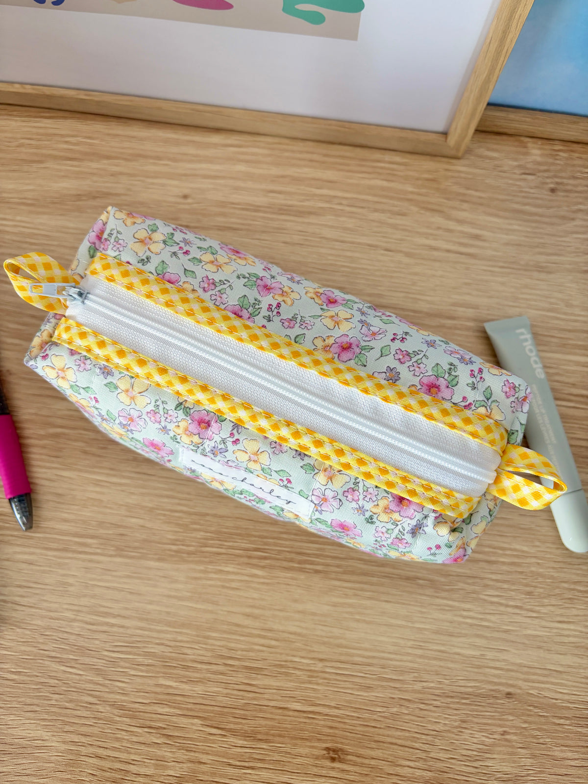 Floral zip pouch bag with white zipper, yellow gingham trim, and side bow accents
