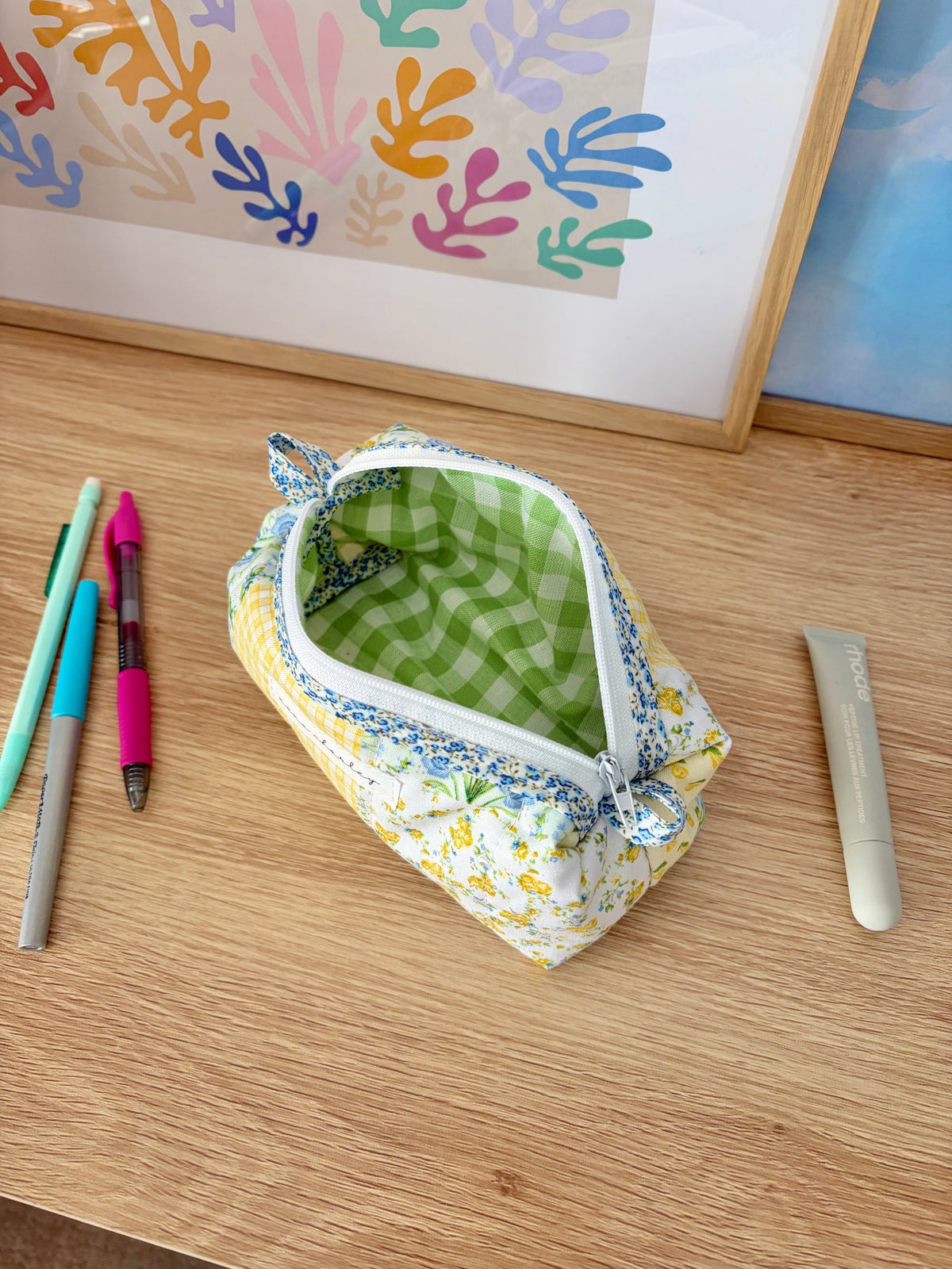 Open patchwork zip pouch with green gingham lining and blue floral outer trim.